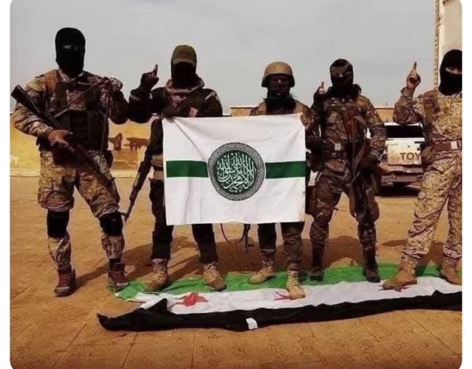 صورة قديمة قيل إنها التُقطت مؤخرًا من سوريا لعناصر من تحرير الشام يدوسون علم الثورة